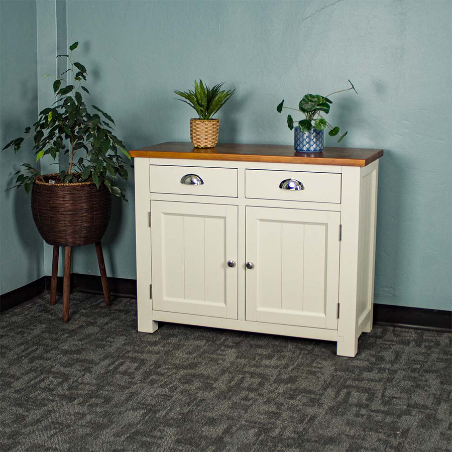 The front of the Alton 2 Door 2 Drawer NZ Pine Buffet. There are two potted plants on top with a free standing potted plant to the left of the sideboard.