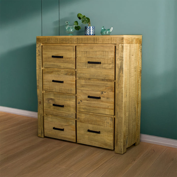 The front of the Amarillo Seven-Drawer Tallboy. There are two glass ornaments on top with a potted plant in between.