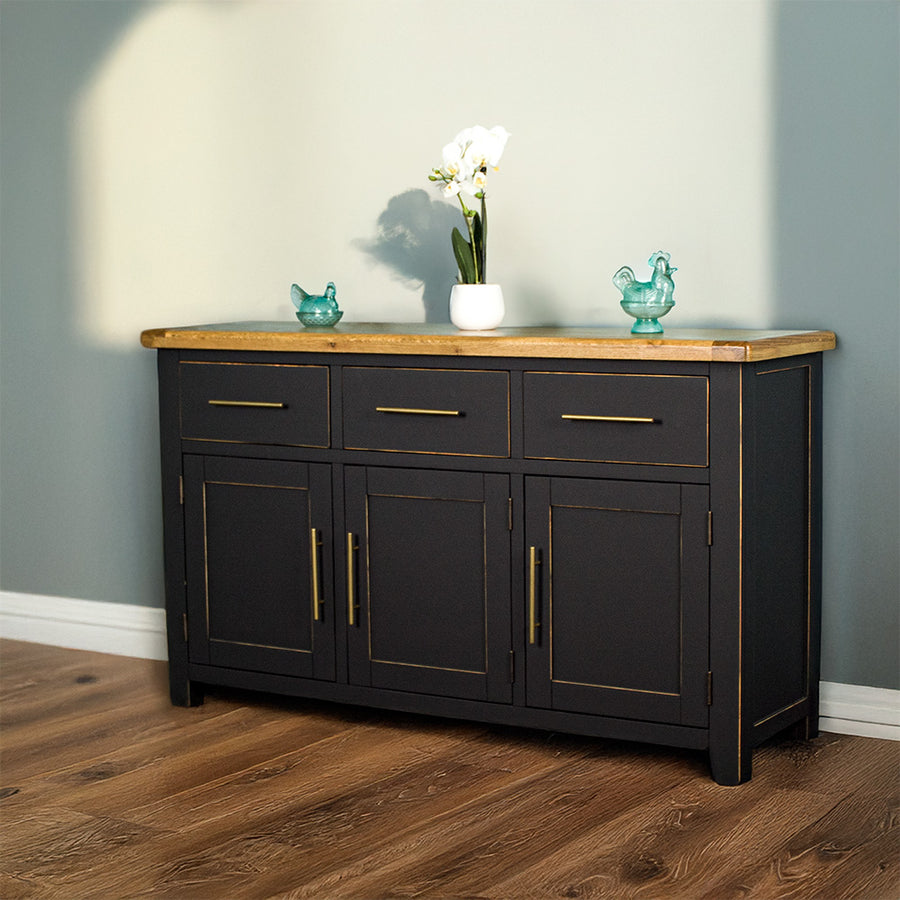 Front view of the Cascais Large Black Buffet. There are two blue glass ornaments and a flower pot on top.