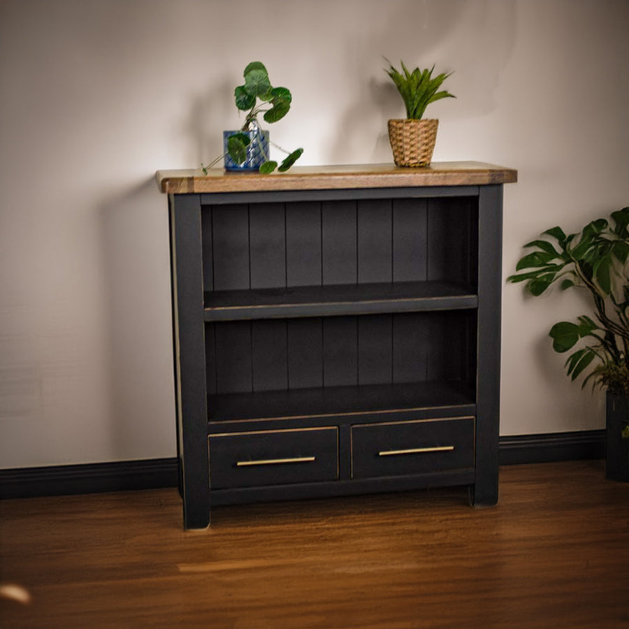 The front of the Cascais Oak Low Bookcase. There are two potted plants on top.