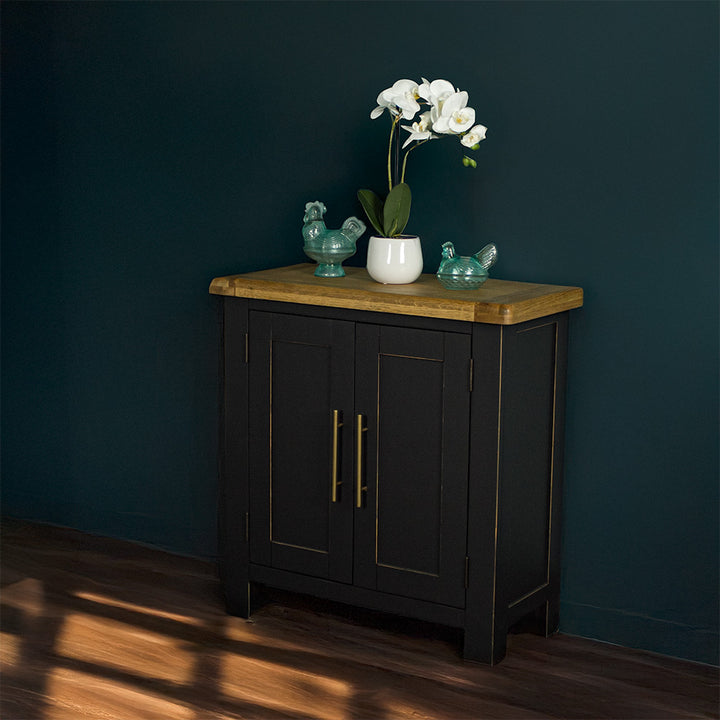 The front of the Cascais Oak-Top Small Sideboard. There are two blue glass ornaments on top with a pot of white flowers in between. 