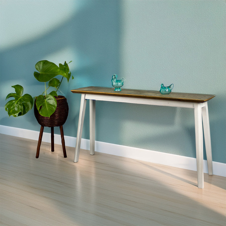 Front view of the Nova Recycled Pine Hall Table. There is a free standing potted plant next to it and two blue glass ornaments on top.