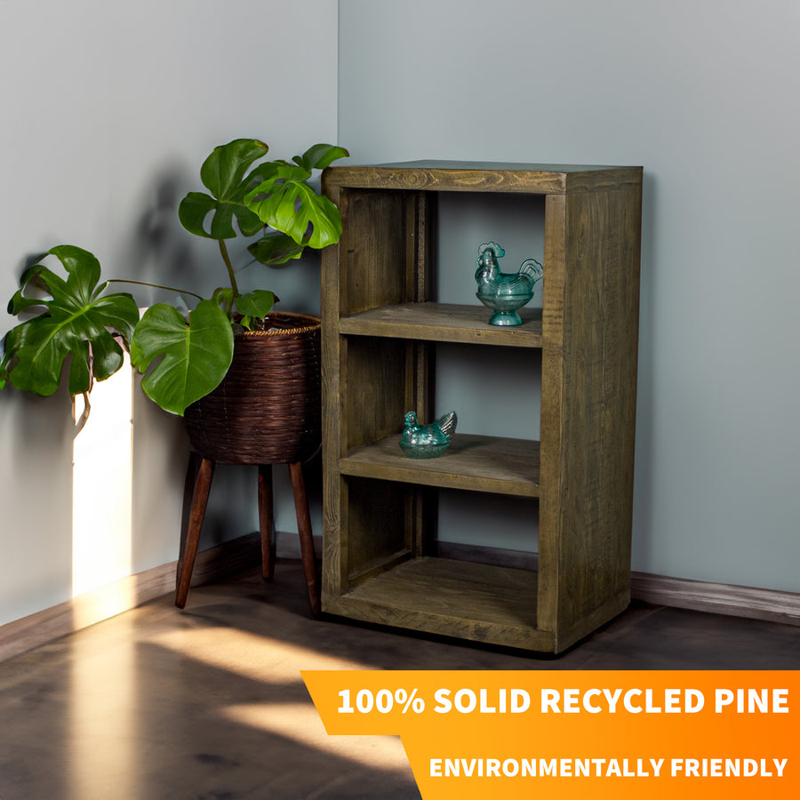The Stonemill Recycled Pine Cube Shelf, with three shelves. There are two blue glass ornaments, one on the middle and one on the top shelf. There is a tall free standing potted plant next to the cube shelf.