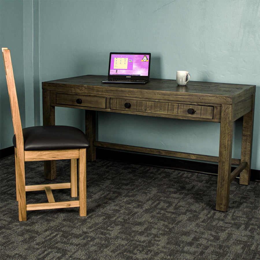 Front of the Stonemill Recycled Pine Desk. There is an oak leather chair in front and a laptop and coffee mug on top.