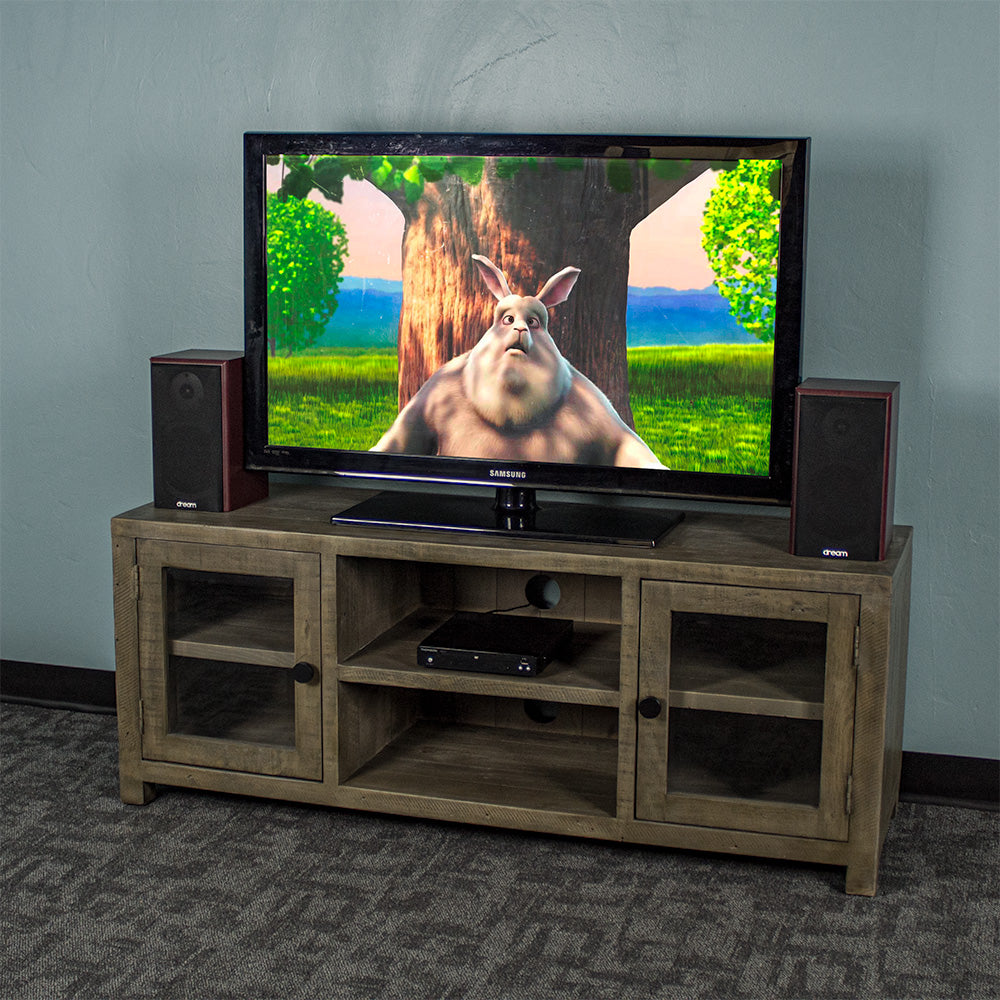 The front of the Stonemill Recycled Pine TV Unit with a TV and two speakers on top. There is a DVD player in the top shelf in the middle.