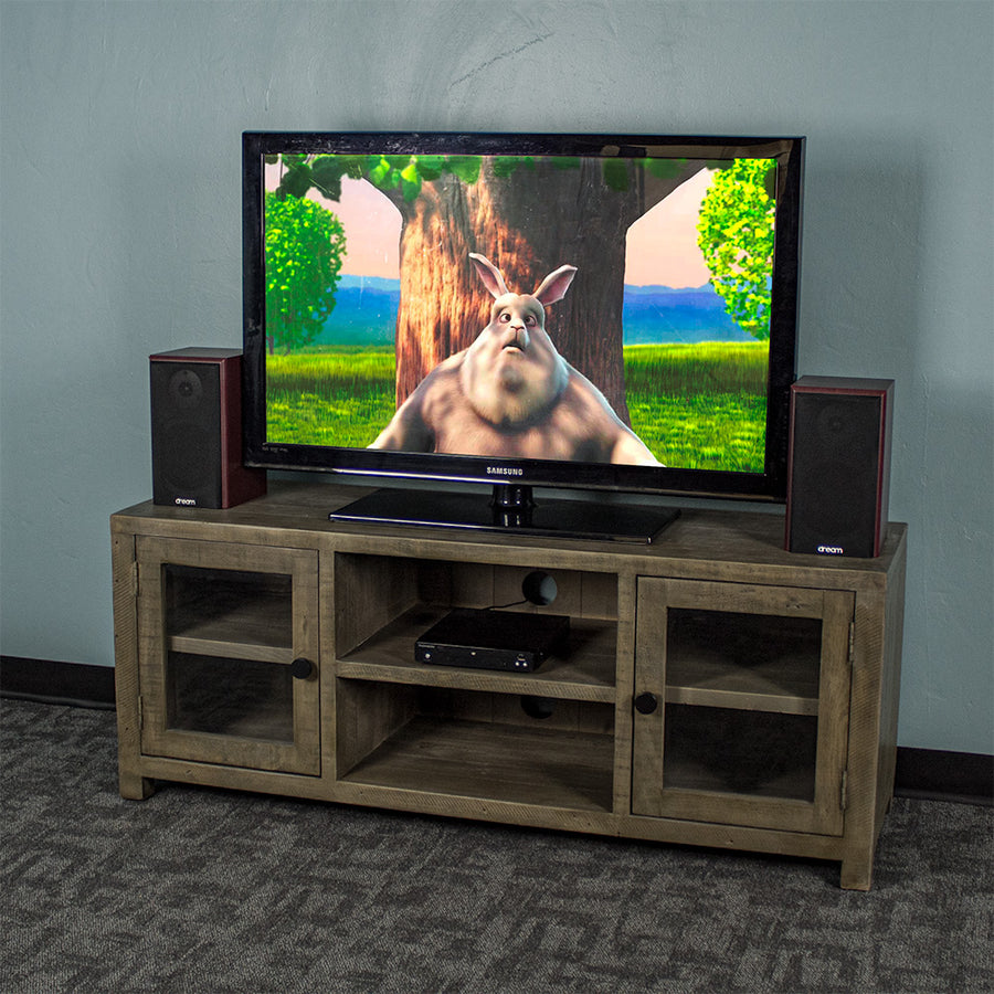 The front of the Stonemill Recycled Pine TV Unit with a TV and two speakers on top. There is a DVD player in the top shelf in the middle.