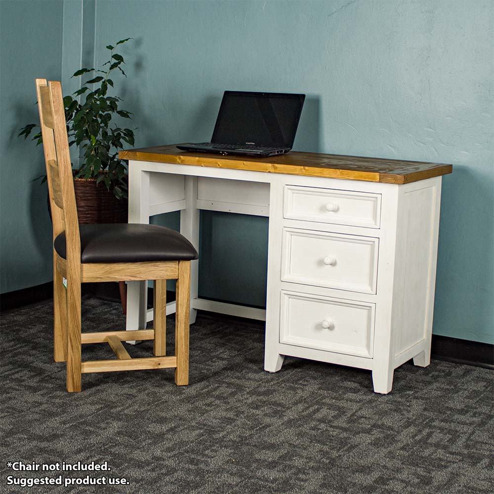 The front of the Tuscan Recycled Pine Small Desk. There is a laptop on top and an oak upholstered dining chair in front. There is a free standing potted plant next to it.