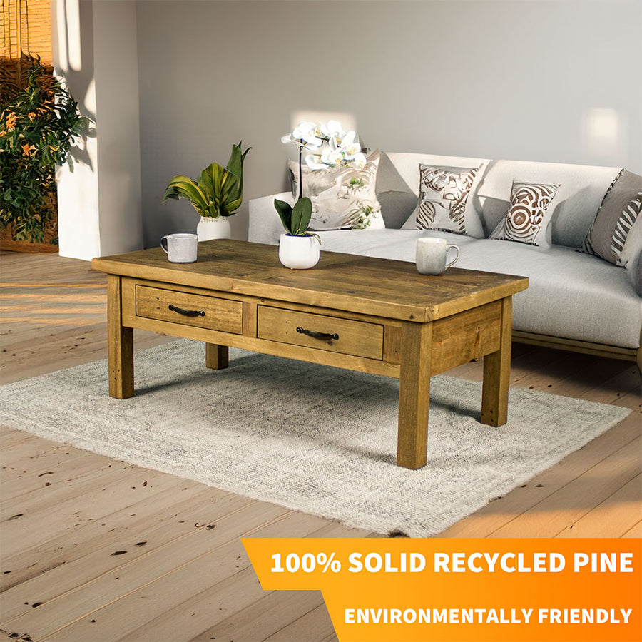 Front view of the Ventura Recycled Pine Coffee Table sitting on a rug. There are two coffee mugs and a pot of white flowers on top.
