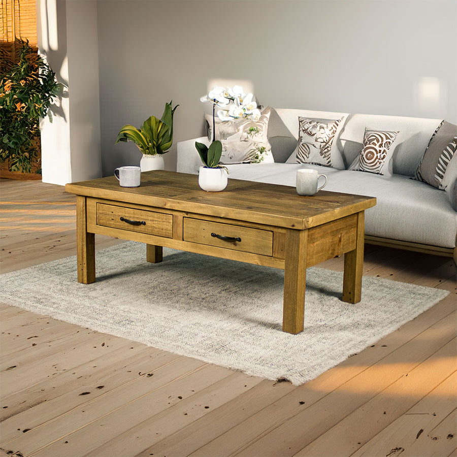 Front view of the Ventura Recycled Pine Coffee Table sitting on a rug. There are two coffee mugs and a pot of white flowers on top.