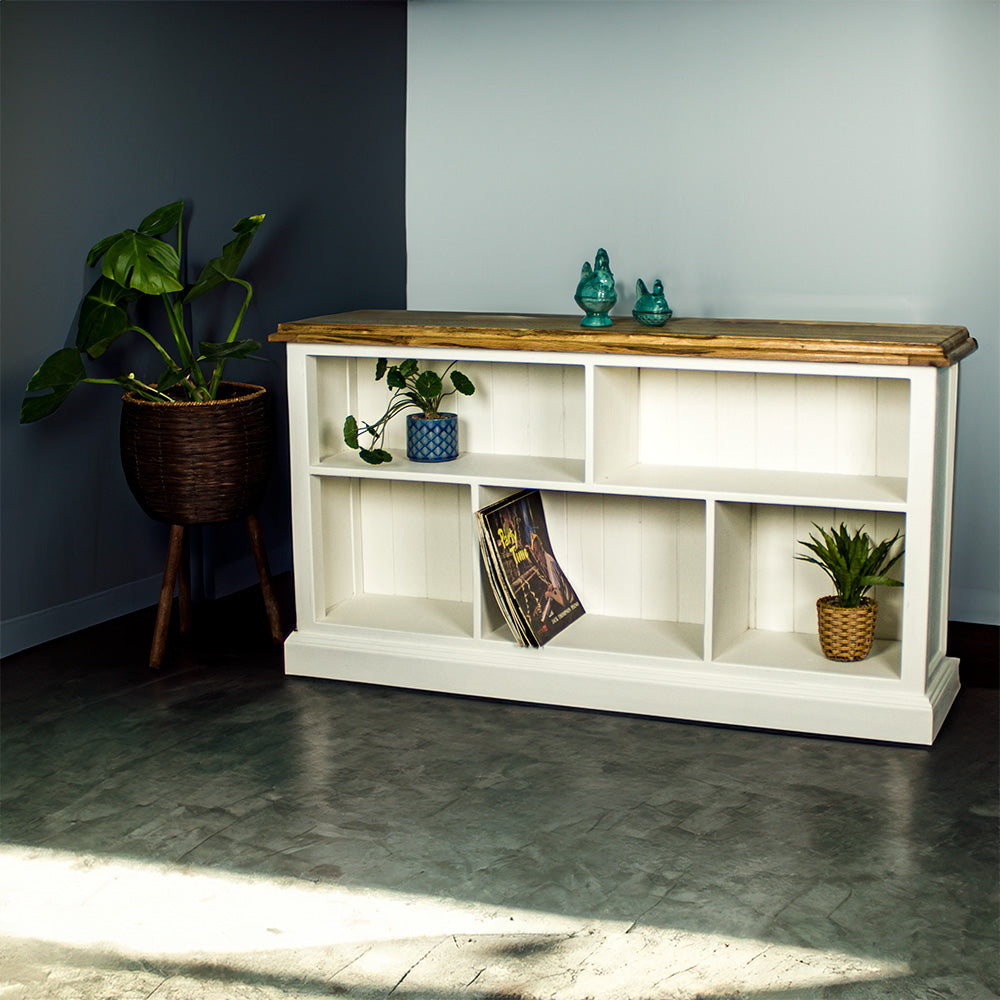 The front of the Versailles Outback Oak Bookshelf (Off White). There are two blue glass ornaments on top. There is a potted plant on the top left shelf, a set of vinyl records on the middle lower shelf and a potted plant on the bottom right shelf. There is a free standing potted plant next to the bookcase.