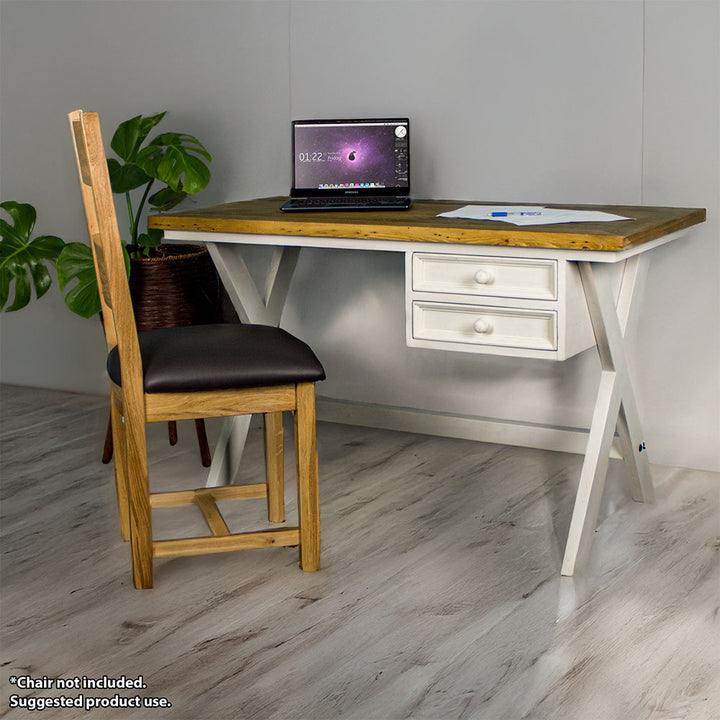 The front of the Byron Recycled Pine Desk. There is a laptop and a pile of papers on top of the desk. There is an upholstered oak chair in front of the desk and a free standing potted plant next to it.