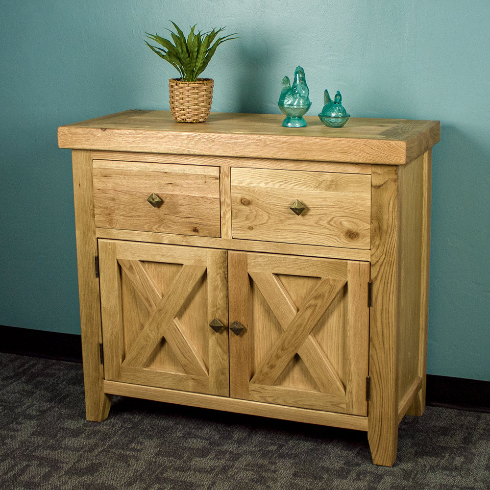 The front of the Maximus Small Oak Buffet. There is a potted plant and two blue glass ornaments on top.