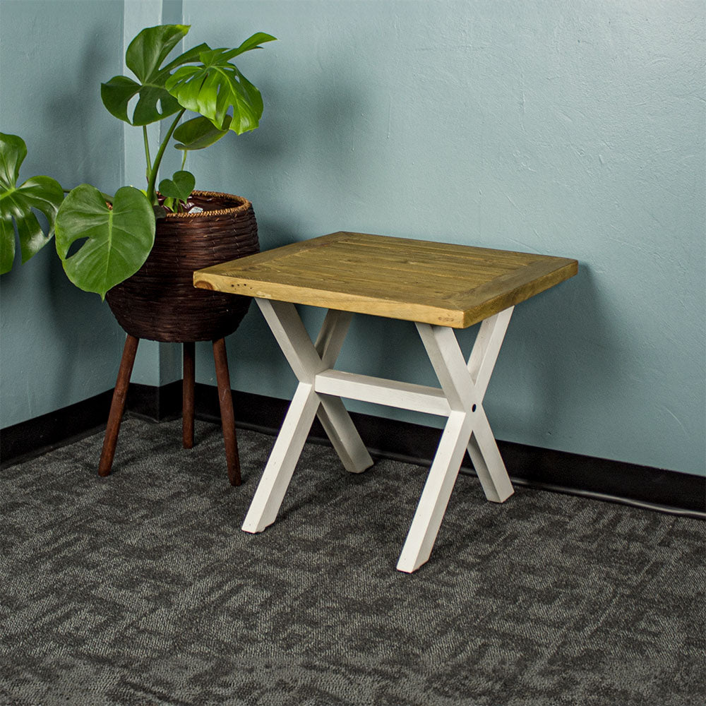 An overall view of the Byron Recycled Pine Lamp Table. There is a free standing potted plant next to it.