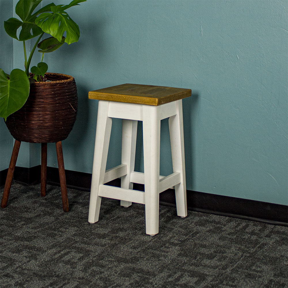 An overall view of the Byron Recycled Pine Stool. There is a free standing potted plant next to the stool.