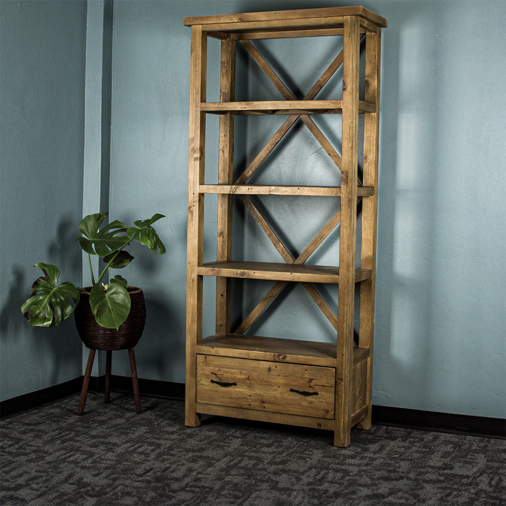 The light brown Ventura Recycled Pine Bookcase, with a standing potted plant next to it. There is text in the corner that says "100% Solid Recycled Pine" and "Environmentally Friendly"