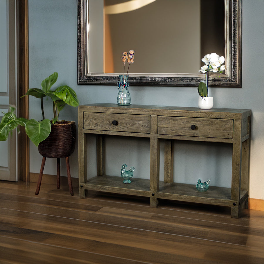 Front view of the brown Stonemill Recycled Pine Hall Table with black circular handles. There are two blue glass ornaments on the lower shelf and two potted plants on the top. There is text in the bottom right corner that says "100% Solid Recycled Pine" and "Environmentally Friendly"