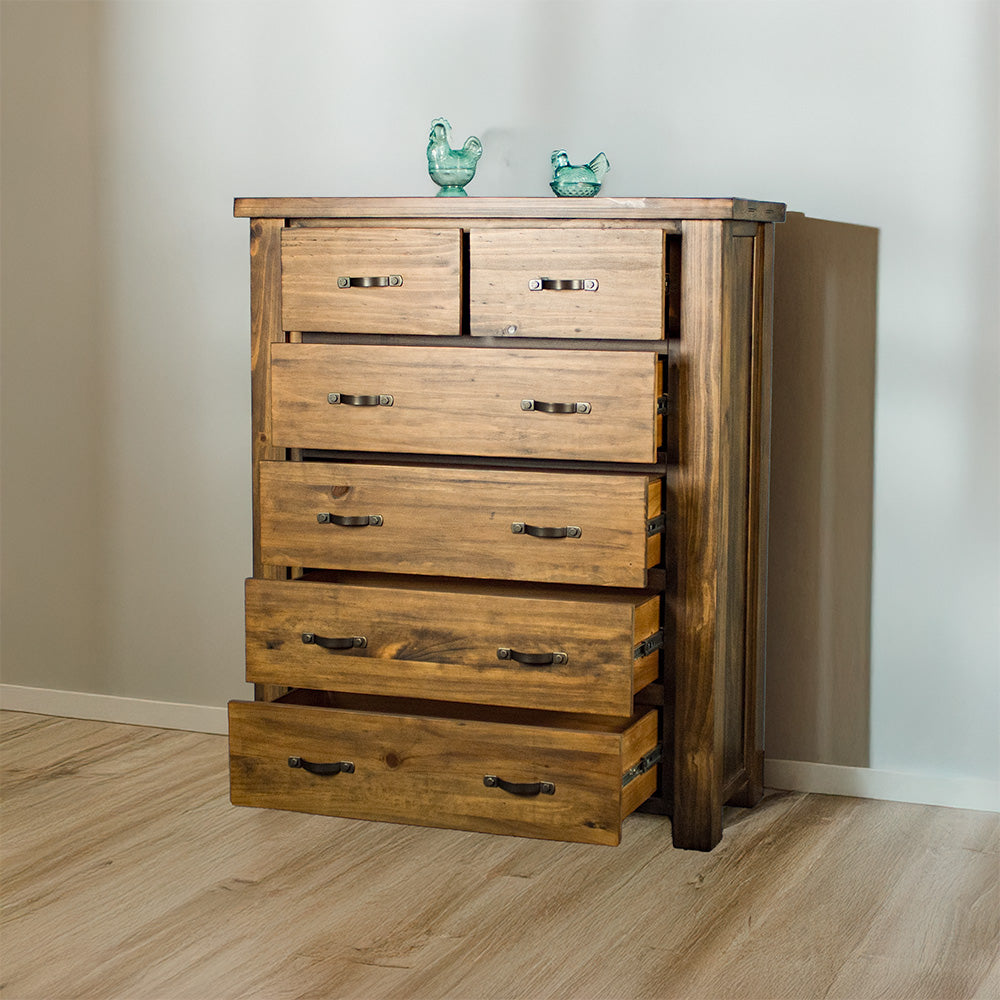 The front of the Botanica Six Drawer Tallboy, with its drawers open. There are two blue glass ornaments on top.