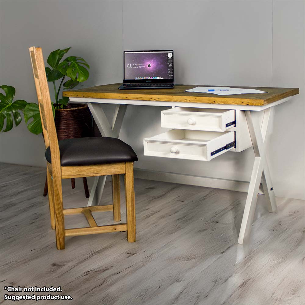 The front of the Byron Recycled Pine Desk with its drawers open. There is a laptop and a pile of paper on top of the desk. There is an upholstered oak dining chair in front of the desk and a free standing potted plant next to it.