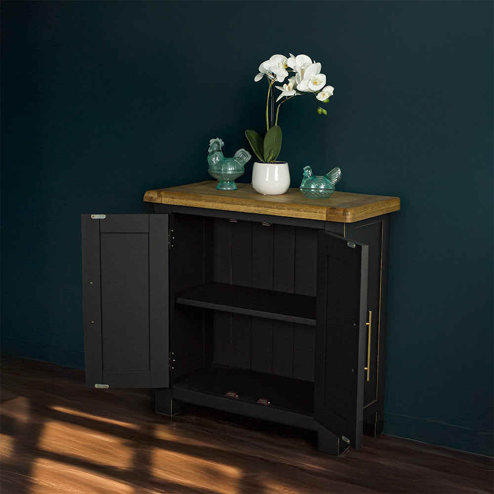 The front of the Cascais Oak-Top Small Sideboard with its doors open. There are two blue glass ornaments on top with a small pot of white flowers in between.