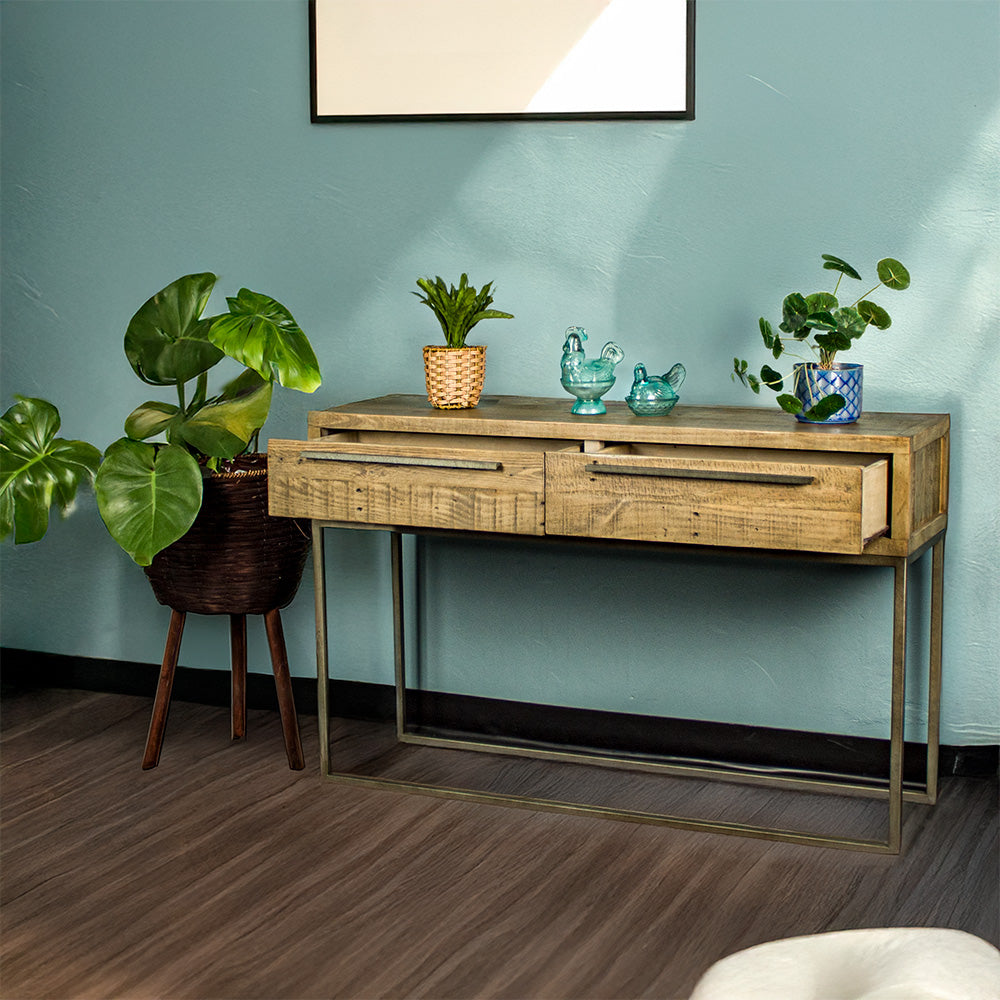 The front of the Monterey Recycled Pine Hall Table with its drawers open. There are two potted plants on top with two blue glass ornaments in the middle. There is a free standing potted plant next to it.