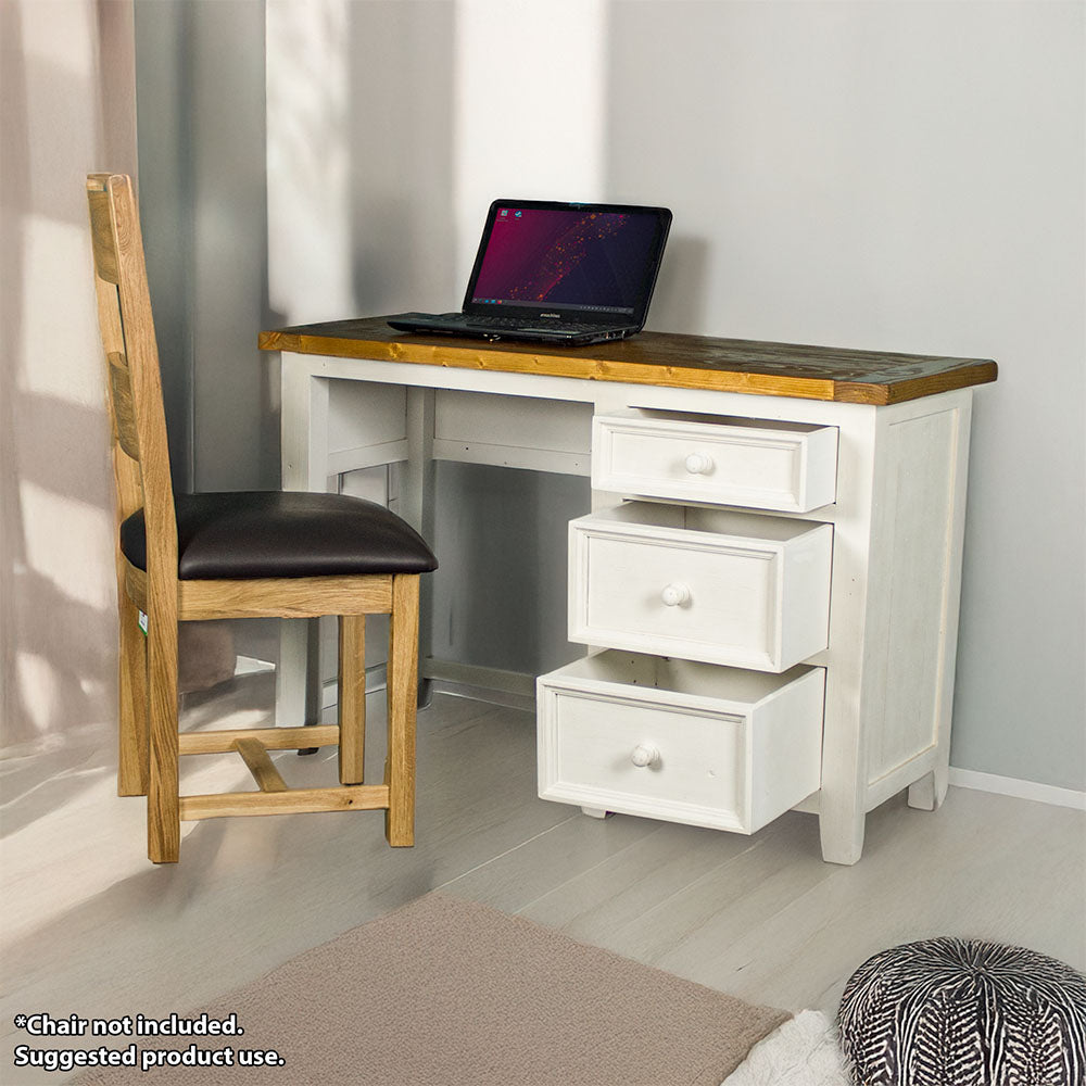 The front of the Tuscan Recycled Pine Small Desk with its drawers open. There is a laptop on top and an oak upholstered dining chair in front. There is a free standing potted plant next to it.