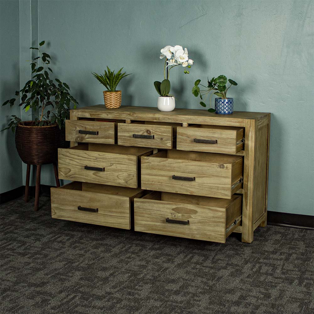 The front of the Vancouver 7 Drawer NZ Pine Lowboy with its drawers open.  There are three potted plants on top and a free standing potted plant next to the lowboy.