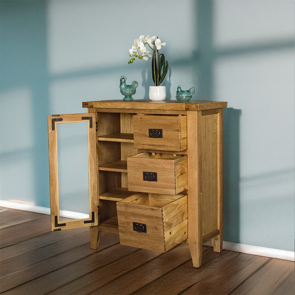 The front of the Yes Compact 1 Door 3 Drawer Oak Buffet with its door and drawers open. There are two blue glass ornaments on top with a potted plant in between.