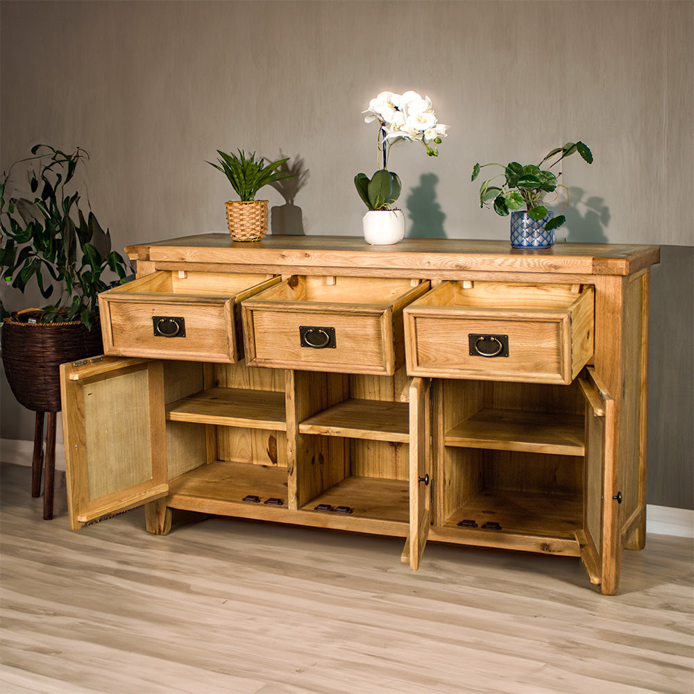 The front of the Yes 3 Door 3 Drawer Oak Buffet with its doors and drawers open. There are three potted plants on top and a free standing potted plant next to the sideboard.