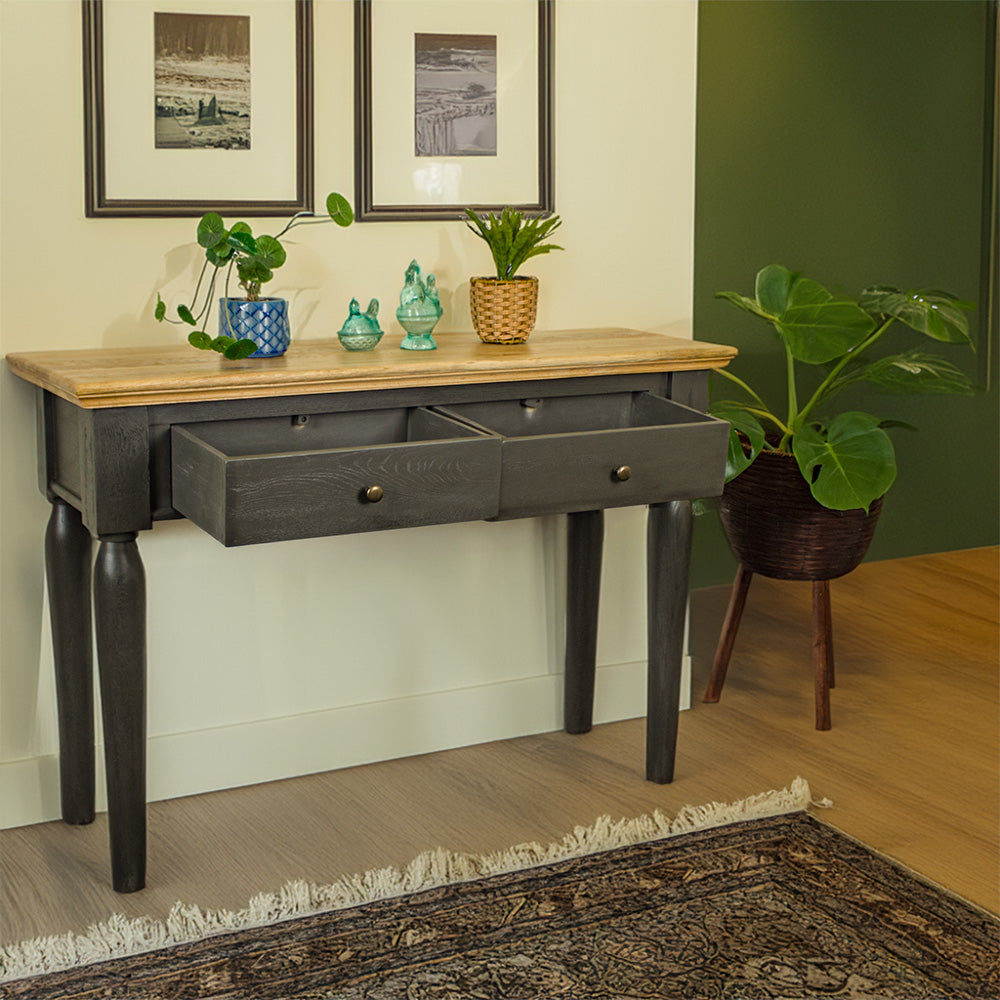 An overall view of the Boston Oak Hall Table - Black with its drawers open. There are two potted plants on top with two blue glass ornaments in between. There is a free standing potted plant next to the table.