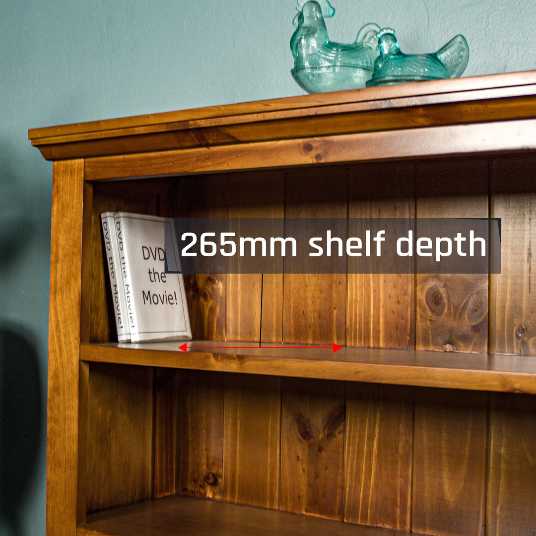 A closer view of the top shelf of the Montreal Short Pine Bookcase. There are two DVD cases on the shelf and two blue glass ornaments in the shape of chickens on top of the bookshelf.