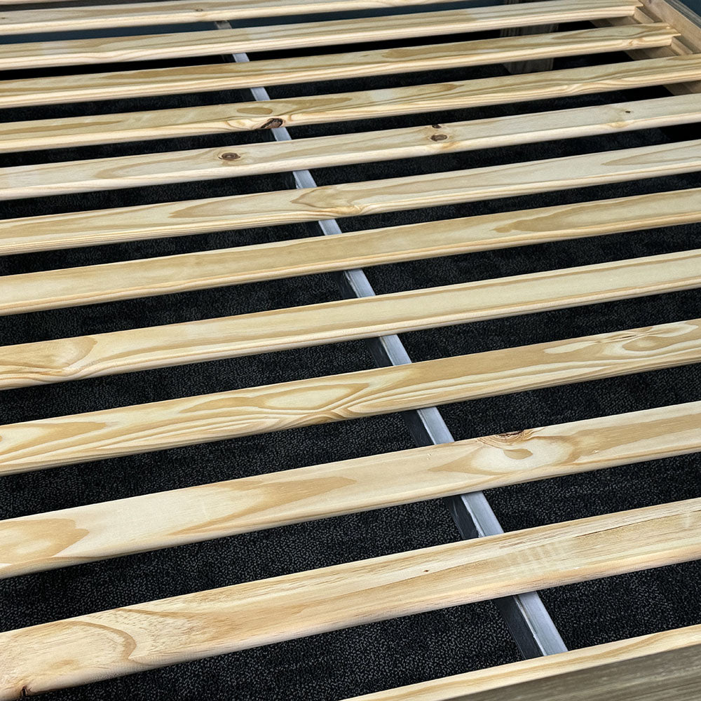 The slats of the Vancouver Queen Size NZ Pine Slat Bed Frame, with a metal support bar running underneath.