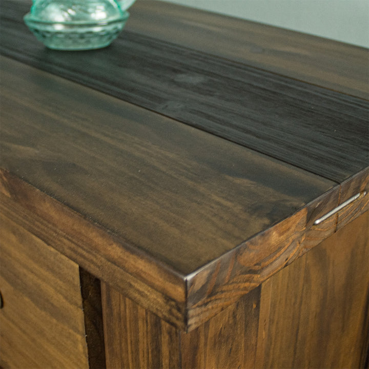 A close up of the top of the Botanica Six Drawer Tallboy, showing the wood grain and colour, as well as the stapled design.