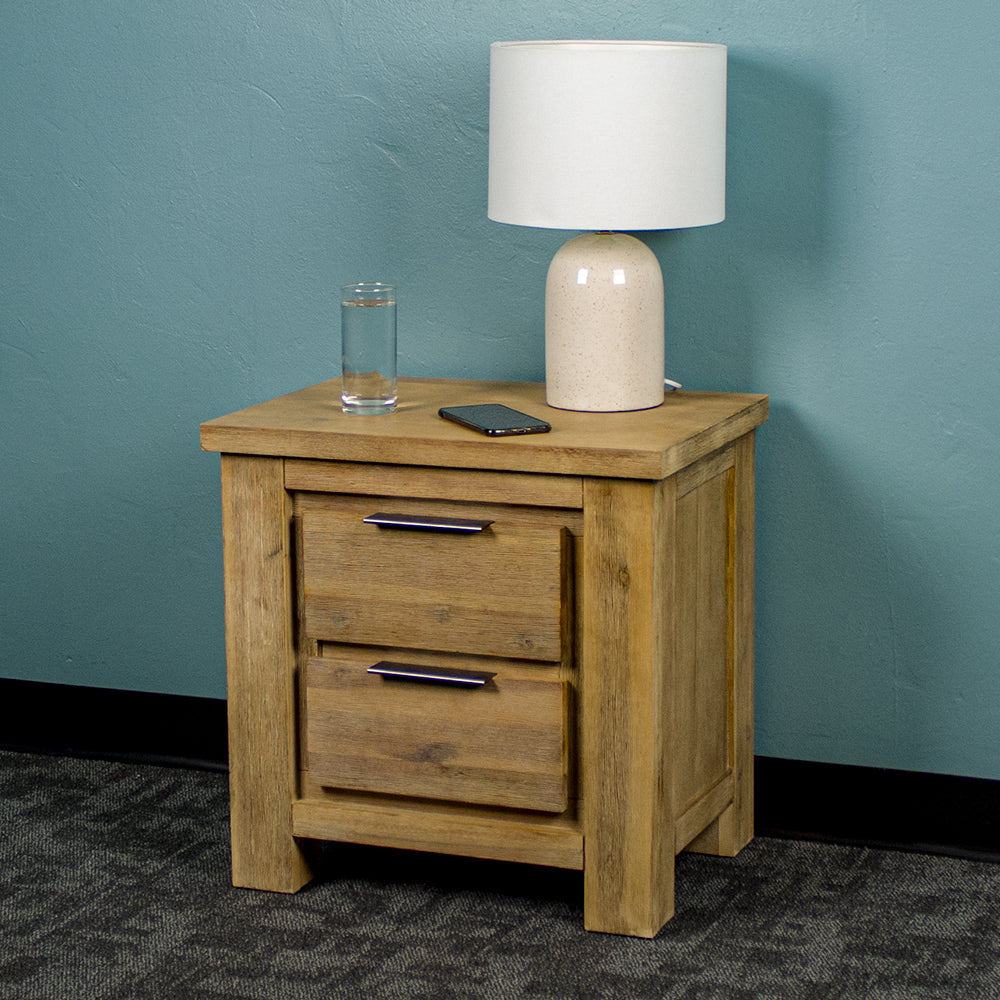 The front of the Mars Two-Drawer Bedside Cabinet. There is a lamp, a glass of water and a phone on top.