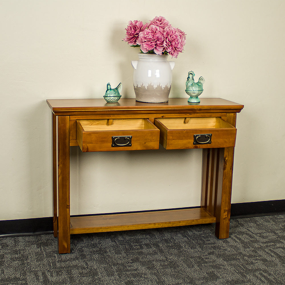 The front of the Montreal Pine Hall Table with its drawers open. There is a large vase on top with two blue glass ornaments on either side.