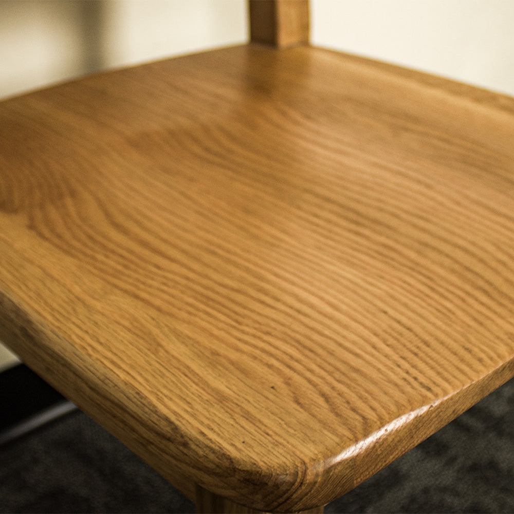 A close up of the top of the seat on the Maximus Oak Dining Chair, showing the wood grain and colour.